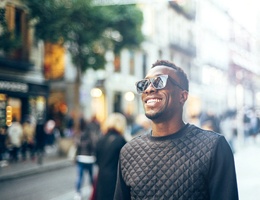 person smiling and walking down a city street after dental crown restoration