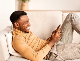 person smiling and looking at their phone after dental crown restoration