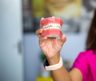 Woman holding model for dentures in Ann Arbor