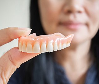 Close-up of woman holding denture in Ann Arbor, MI