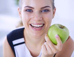 Woman smiling while holding an apple