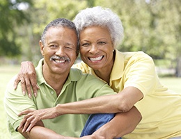 Older couple with dental implants in Ann Arbor smiling outside