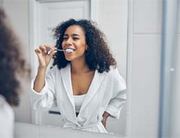 a person brushing their teeth and looking in a bathroom mirror