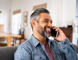 Man smiling while talking on phone at home