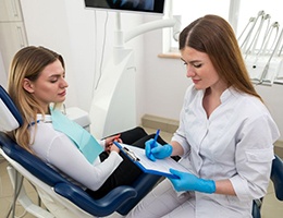 Dental team member taking notes while sitting close to patient