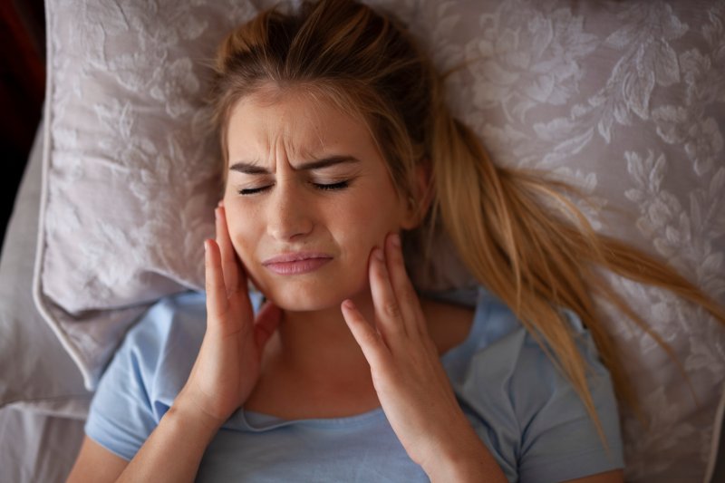 Woman experiencing TMD pain after waking up