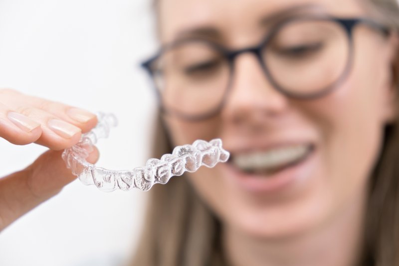 Smiling woman holding Invisalign tray