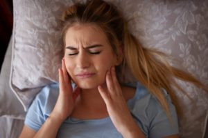 Woman suffering from jaw pain due to TMD.