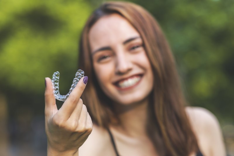 patient holding Invisalign tray and smiling 
