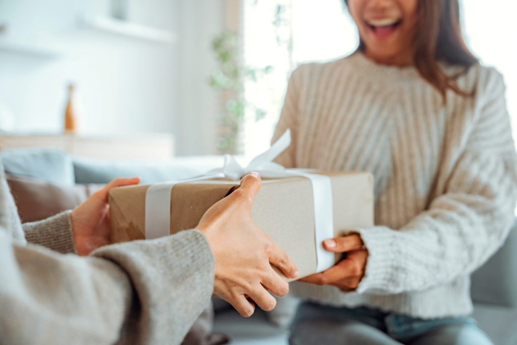 Woman smiling while receiving present at home