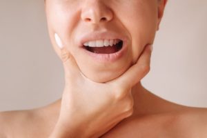 Woman touching her jaw, wearing pained expression